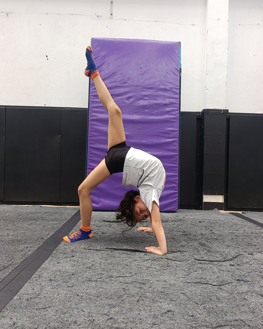 Niña haciendo el puente de capoeira sobre la colchoneta en una clase de Brinca Playing