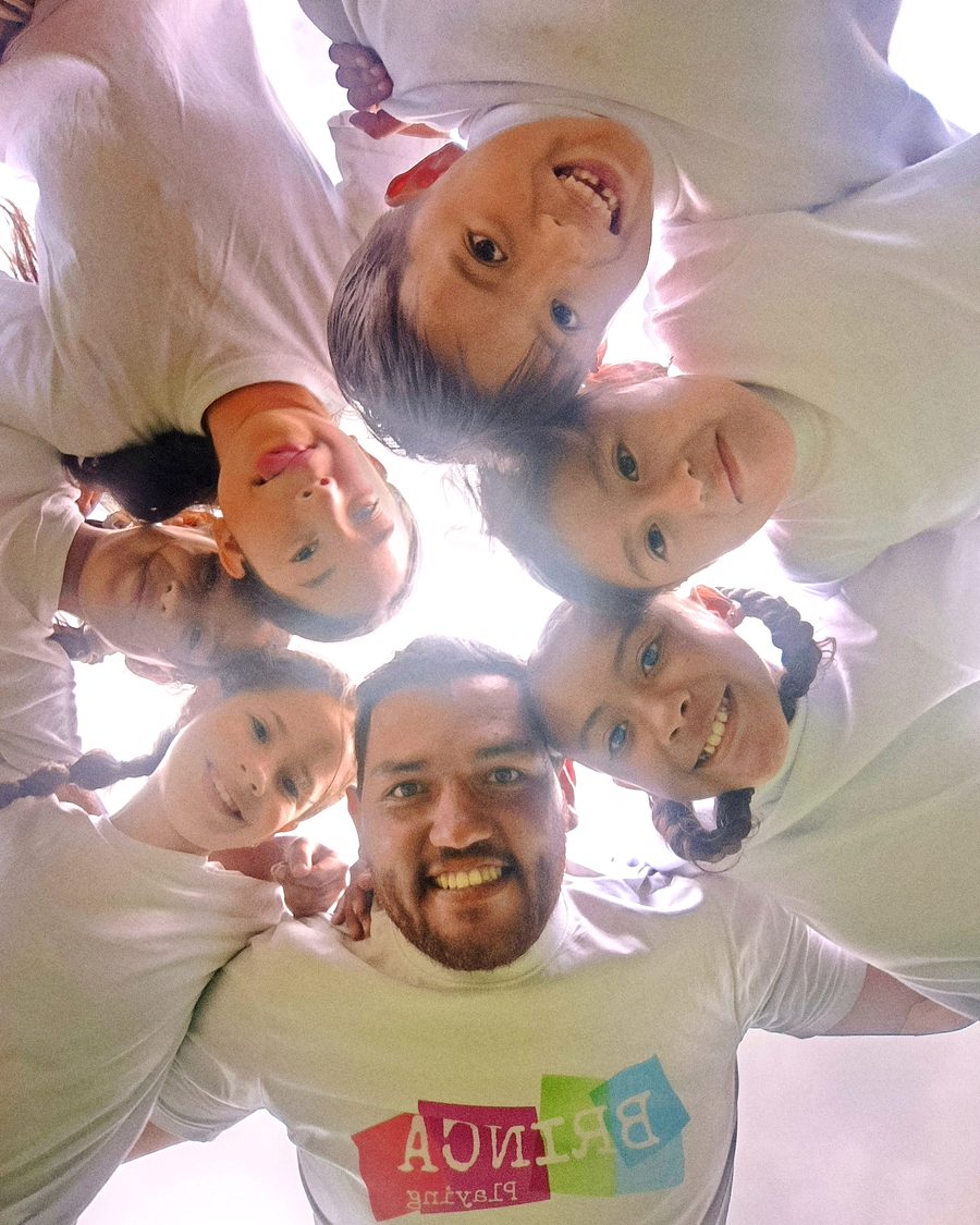 Instructor de Brinca Playing y grupo de niñas sonriendo en círculo